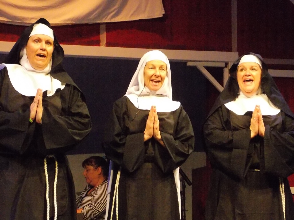 Three female actors in nuns habits with their hands folder in prayer