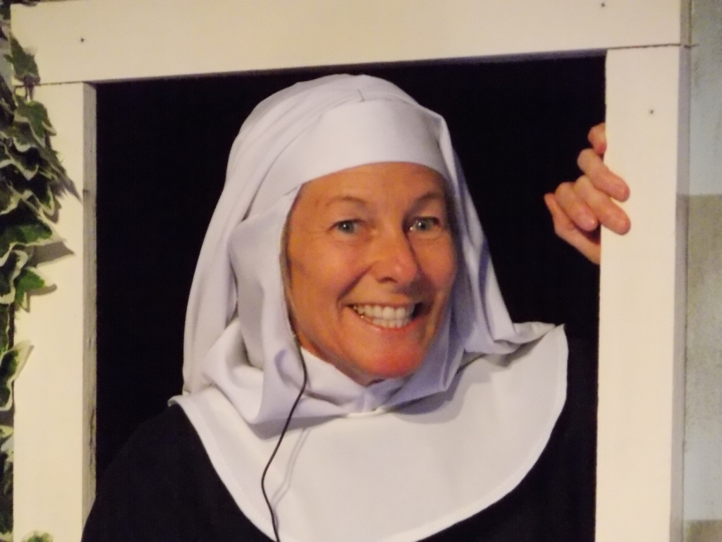 Female actor in a nun habit peeking through a windo